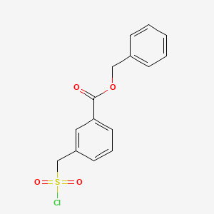 molecular formula C15H13ClO4S B14072015 Benzyl 3-[(Chlorosulfonyl)methyl]benzoate 