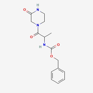 molecular formula C15H19N3O4 B1463393 benzyl N-[1-oxo-1-(3-oxopiperazin-1-yl)propan-2-yl]carbamate CAS No. 1214658-70-4