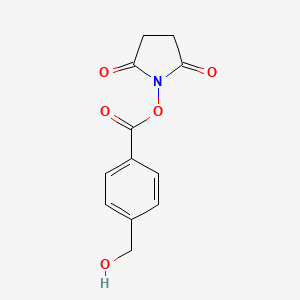 molecular formula C12H11NO5 B15159034 2,5-Pyrrolidinedione, 1-[[4-(hydroxymethyl)benzoyl]oxy]- CAS No. 663169-64-0