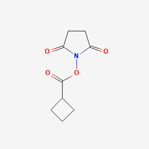 molecular formula C9H11NO4 B3096523 1-[(Cyclobutylcarbonyl)oxy]pyrrolidine-2,5-dione CAS No. 128611-94-9